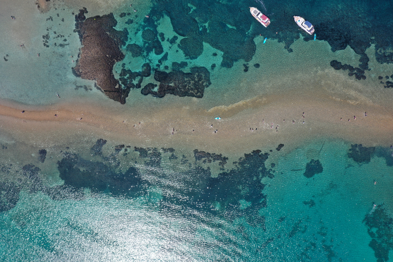 Balıkesir'in Ayvalık ilçesinde yaz aylarında denizin sığlaşmasıyla Cunda Adası ile Maden Adası arasında oluşan yürüyüş güzergahı, tatilcilerin ilgisini çekiyor.
