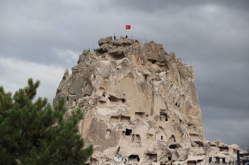<p><b>KAYALARIN İÇİNDEKİ YAŞAM ALANI</b></p><p><br></p><p>Kalenin önemli özelliklerinden biri, doğal kaya kütlesinin farklı dönemlerde insanların ihtiyaçlarına göre şekillendirilmiş olması.</p><p><br></p><p>Roma döneminden itibaren kayaların içine odalar, evler, sığınaklar, depolar, sarnıçlar, mezarlar ve mahzenler oyuldu. </p><p>Kale ve çevresindeki kaya mekânları, yalnızca barınma amacıyla değil, farklı ihtiyaçlar için de kullanıldı.</p><p><br></p><p>Uçhisar Belediyesi, kale ve çevresindeki kayalara oyulmuş mağaralar, ibadethaneler ve yaşam alanlarının erken Hristiyanlık döneminin izlerini taşıdığını belirtiyor.</p>