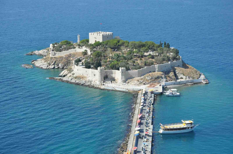<p>Kuşadası'nın tarihî limanıyla bağlantılı olan Güvercinada'nın geçmişi, bölgede Bizans döneminden itibaren gelişen yerleşim ve deniz ticareti tarihinin bir parçasını oluşturuyor. 13. yüzyılda Bizans ile Latinler arasında yapılan anlaşmaların ardından Cenevizli tüccarların Ege'de ticari ayrıcalıklar kazanması, bölgedeki limanların önemini artırdı.</p>